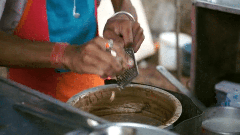 Shantanu the chai guy grating fresh ginger into a pot of chai at his stall in Pune